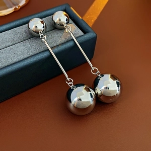 Close-up of silver metal ball drop earrings in a luxury jewelry box display