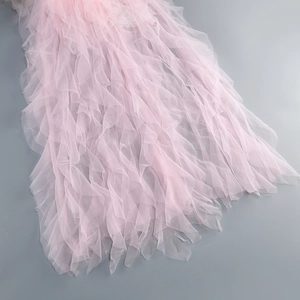 Detail of layered pink ruffle mesh fabric and soft lace texture on a long dress