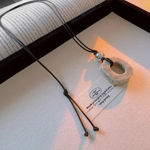 Irregular marble-textured pendant necklace displayed on an open vintage book page