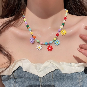 Close-up of colorful beaded necklace with vibrant flower charms on a female model