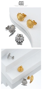 Detailed view of sunflower stud earrings in gold and silver plating on white display