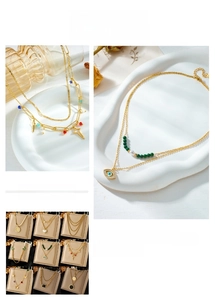 Detail of layered gold necklaces featuring evil eye, heart, and butterfly pendants