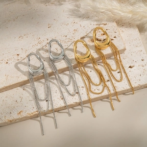 Detail of vintage geometric tassel earrings in gold and silver on a textured stone base