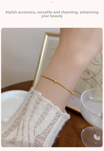 Detail of minimalist gold snake chain bracelet with polished beads worn on woman wrist