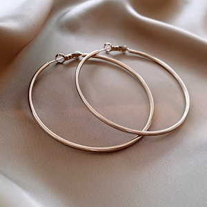 Close-up of polished gold circular hoop earrings resting on champagne silk fabric