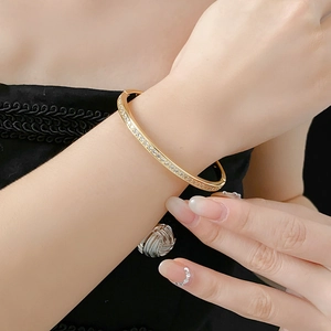 Detailed view of a gold-tone bangle with pave-set cubic zirconia on a model's wrist