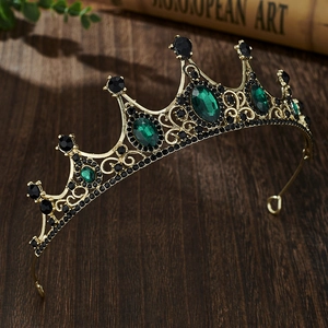 Detail of a vintage golden crown featuring green oval gemstones and intricate filigree