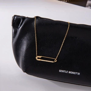 Elegante collana con ciondolo a graffetta dorata e cristalli su una borsa