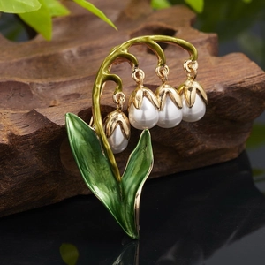Macro detail of lily of the valley brooch with white pearls and green enamel leaves