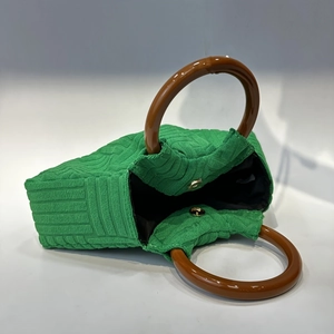 Detail view of green fabric clutch bag with brown wooden handle and magnetic closure
