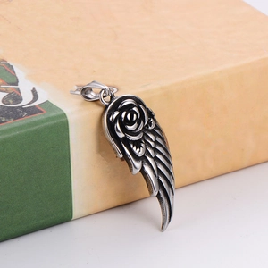 Macro detail of silver feather wing pendant with a vintage carved rose relief design
