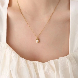Elegant gold pearl necklace featuring a white teardrop pendant on a fine link chain
