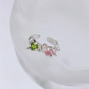 Close-up of adjustable silver ring with green and pink gemstones in lava design