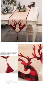 Detail of Christmas table runner with reindeer embroidery, plaid trim, and red tassels