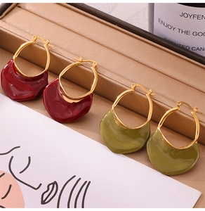 Detail of irregular resin drop earrings in burgundy and olive green on a leather tray