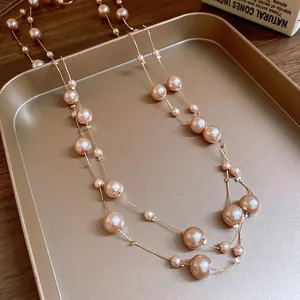 Double-layered pearl necklace with golden chain on a luxury tray over a dark wooden desk