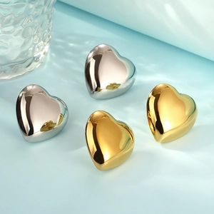 Macro shot of minimalist hollow heart stud earrings in polished gold and silver finishes