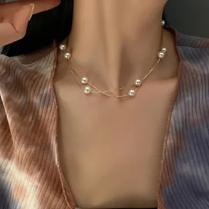 Close-up of double-layer gold necklace with white pearls on model neckline