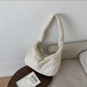 Close-up of creamy white soft padded cloud bag with plush down cotton texture on a sofa