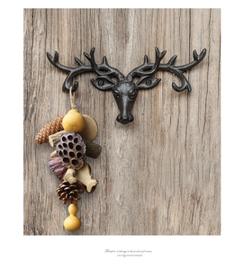 Close-up of vintage cast iron antler wall hook with natural pinecone hanging decor