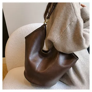 Detailed close-up of dark brown leather texture and metal ring buckle on tote bag