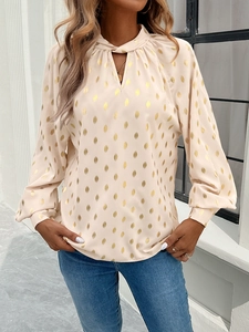 Close-up of beige long sleeve blouse with gold foil dots, twist neck and keyhole detail