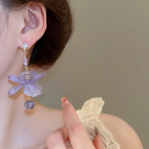 Close-up of purple resin flower earrings with crystals on a model for a romantic look