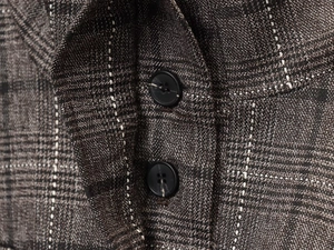 Détail macro du tissu à carreaux en laine mélangée avec un bouton noir classique