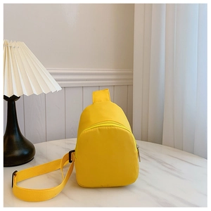 Detailed view of bright yellow kids crossbody chest bag on marble table with lamp decoration