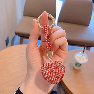 Close-up of heart-shaped keychain with red rhinestones and golden metal ring
