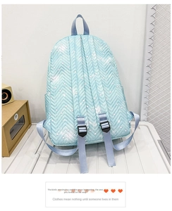 Detalle de la mochila acolchada azul claro con patrones de corazones y correas ajustables