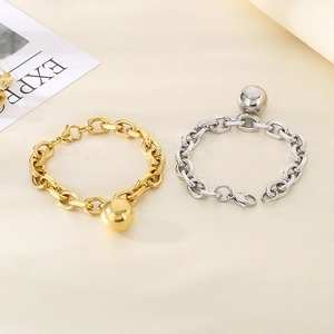 Detail view of chunky gold and silver chain bracelets with polished metal sphere charms