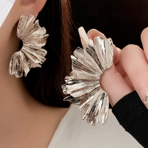 Detailed view of silver metallic earrings featuring unique fan-shaped pleated leaf texture