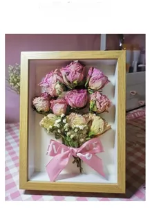 Detailed view of wooden 3D shadow box with dried pink roses and LOVE ribbon bow