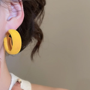 Gros plan d'une créole jaune floquée en forme de C portée par un mannequin pour un look chic