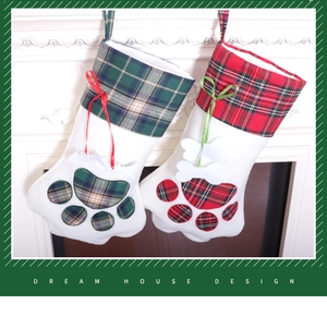Detail of red and green plaid paw-shaped Christmas stockings with bone tags on a fireplace