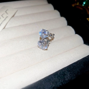 Macro shot of silver zircon ear cuff on a beige jewelry box with brilliant light