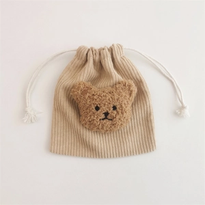 Detail of beige corduroy drawstring pouch with a cute brown plush bear decoration