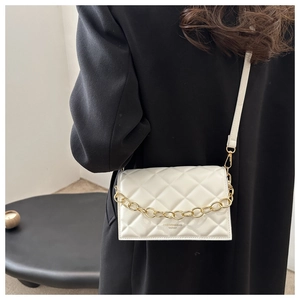 Close-up of white quilted crossbody bag with gold chain and fashion lettering