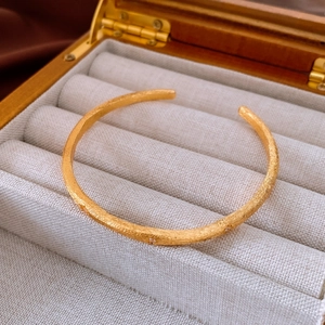 Close-up of vintage gold open bangle with brushed texture and zircon floral accents