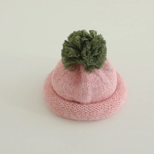 Pink knitted beanie for kids with green pom-pom and rolled edge winter hat detail