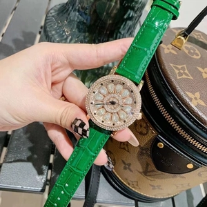 Detailed close-up of a rotating gemstone dial and green leather strap luxury watch
