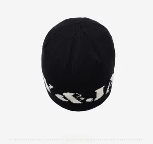 Detailed top view of black knit beanie featuring white letter embroidery and patterns