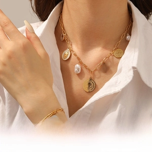Detail of vintage gold layered necklace with cross charms, portrait medals and pearls