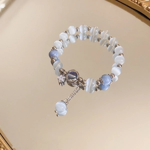 Elegant opal beaded bracelet with zircon star charm and blue pendant on mirrored surface