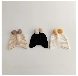Detailed view of three soft knit baby hats in beige, black and white for winter warmth