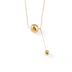 Macro shot of gold Y-shaped necklace with polished spheres on a sleek snake chain