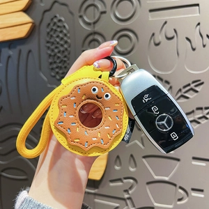 Porte-clés créatif en cuir beignet jaune avec lanière tressée à côté de clés de voiture