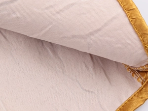 Detailopname van lichtroze gebreide stof met textuur en gouden satijnen rand