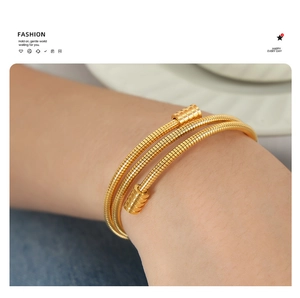 Detail of gold snake chain bracelet featuring multilayered spiral design and polished ends